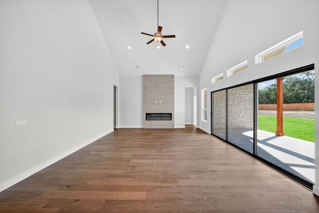 Unfurnished living room featuring high vaulted ceiling, a tile fireplace, light wood-style flooring, ceiling fan, and recessed lighting | Image 5