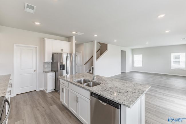 Open kitchen with large island, 42" upper cabinets, quartz countertops, tile backsplash, microwave vent out, designer hardware. An abundance of storage. Blinds, Fridge, Washer & Dryer INCLUDED in every home. | Image 4