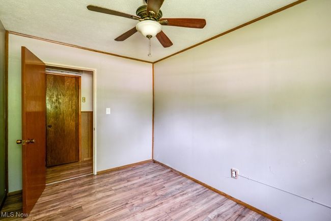 Unfurnished room with light wood-style floors, baseboards, a ceiling fan, and ornamental molding | Image 20