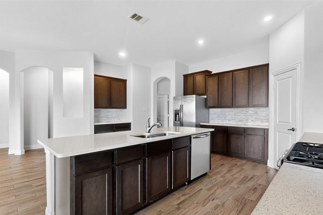 Kitchen with appliances with stainless steel finishes, arched walkways, tasteful backsplash, light wood finished floors, and recessed lighting | Image 7