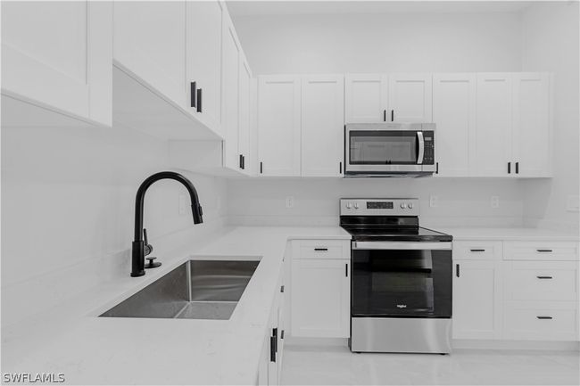 Kitchen featuring sink, tasteful backsplash, white cabinetry, and appliances with stainless steel finishes | Image 35