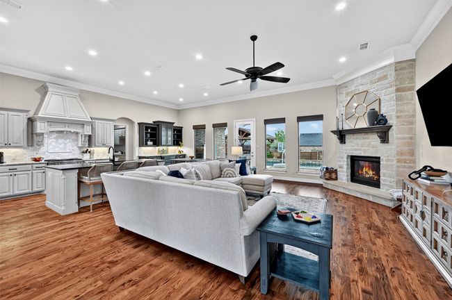 Living room with a fireplace, a ceiling fan, recessed lighting, ornamental molding, and wood finished floors | Image 6