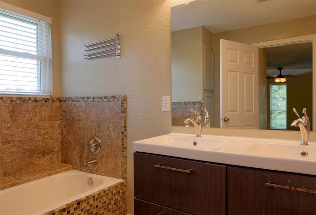 Full bathroom with a ceiling fan, vanity, and a relaxing tiled tub | Image 19