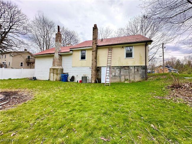 Rear view of property with a chimney, a tiled roof, fence, a yard, and cooling unit | Image 39