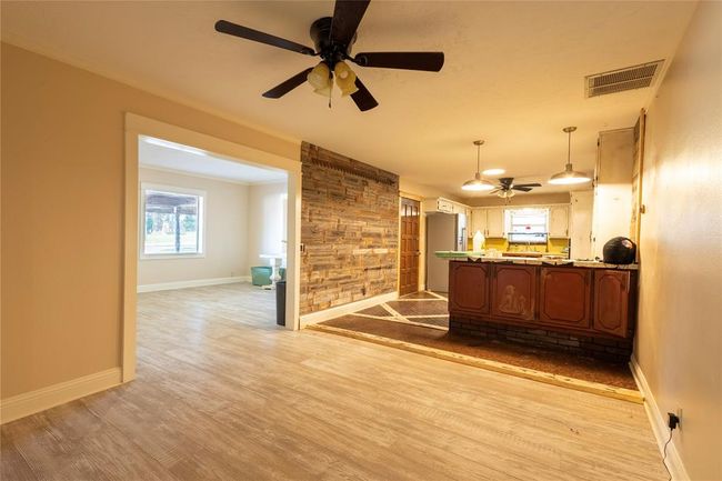 Kitchen with stainless steel refrigerator with ice dispenser, a ceiling fan, light wood-type flooring, baseboards, and pendant lighting | Image 7