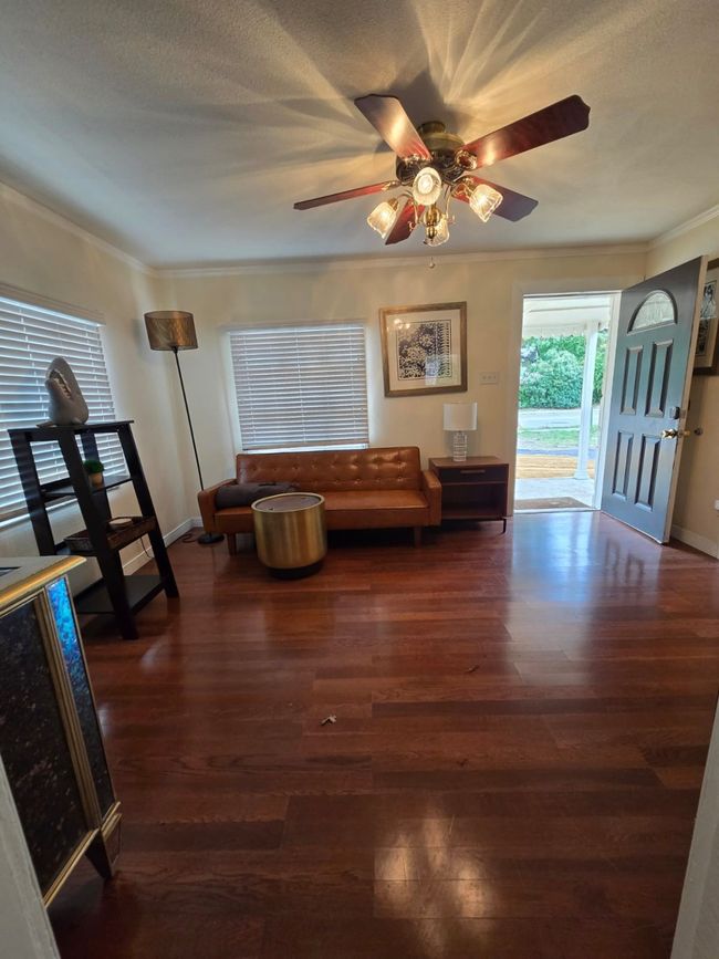 Living area featuring dark wood-type flooring, a ceiling fan, and ornamental molding | Image 24