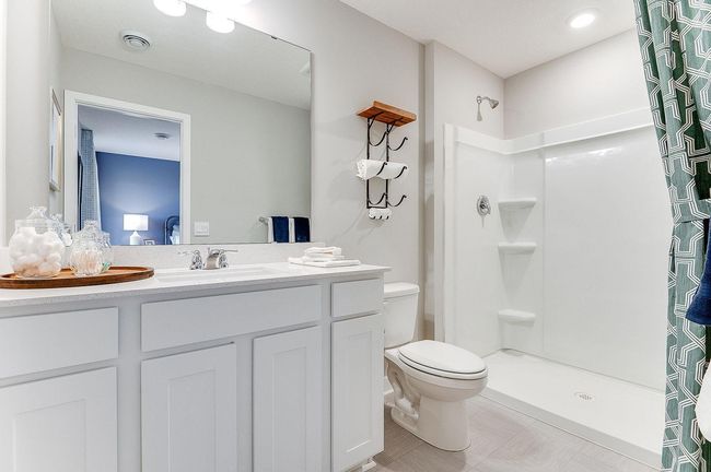 The en suite conveniently has a step in shower. Photo of a similar layout model home, layout and colors will vary. | Image 6