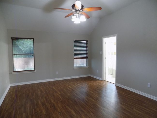 Empty room featuring ceiling fan, lofted ceiling, and dark wood-style flooring | Image 21