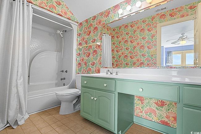 Full bathroom featuring visible vents, shower / bathtub combination with curtain, toilet, vanity, and wallpapered walls | Image 37