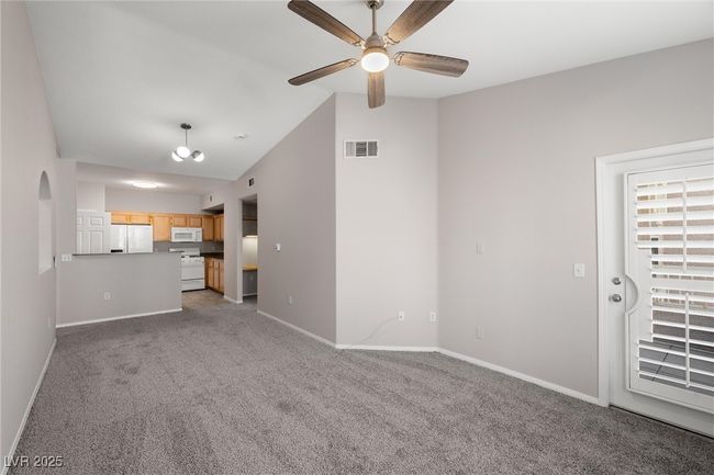 Unfurnished living room featuring visible vents, ceiling fan, baseboards, vaulted ceiling, and carpet | Image 12