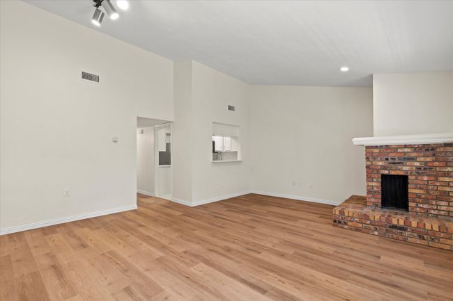 The living room features a wood burning fireplace and vaulted ceiling | Image 8