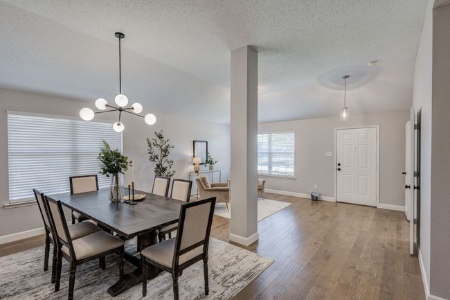 Dining space featuring wood finished floors, baseboards, a textured ceiling, and a chandelier | Image 6