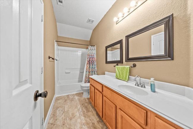 Full bathroom with vanity, shower / tub combo with curtain, toilet, and a textured wall | Image 33