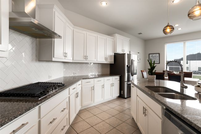 Kitchen featuring wall chimney range hood, appliances with stainless steel finishes, white cabinetry, and a sink | Image 12
