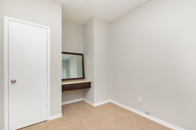 Unfurnished bedroom with carpet floors, built in desk, and a textured ceiling | Image 10