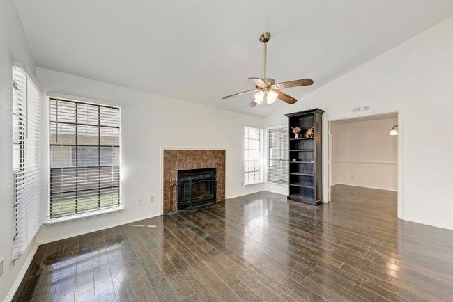 Unfurnished living room with a fireplace, wood finished floors, and a ceiling fan | Image 6