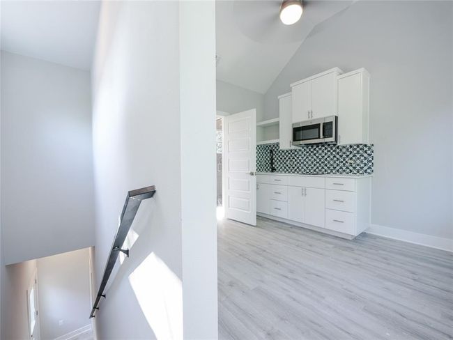 Kitchen featuring stainless steel microwave, open shelves, backsplash, a ceiling fan, and white cabinetry | Image 27