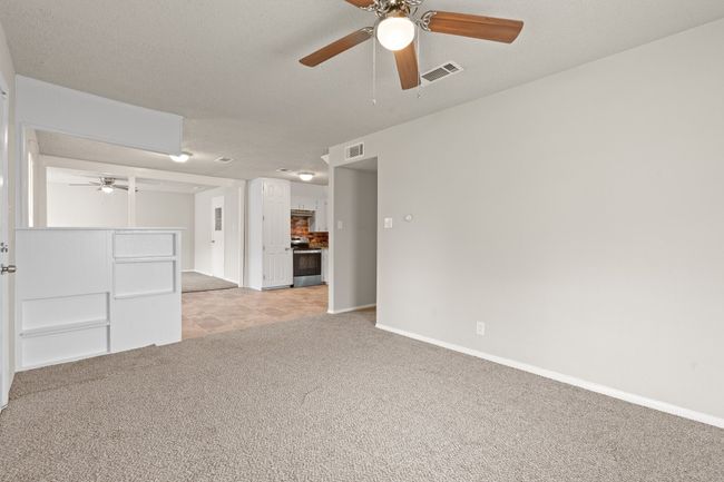 Unfurnished living room featuring light colored carpet and ceiling fan | Image 4