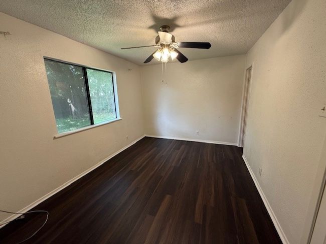 Spare room featuring wood finished floors, a textured ceiling, a ceiling fan, and a textured wall | Image 8