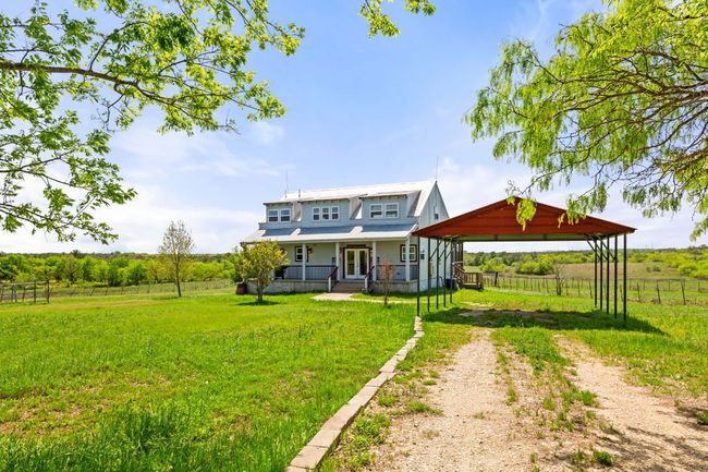 Rear view of property featuring fence, a gazebo, driveway, french doors, and a yard | Image 4