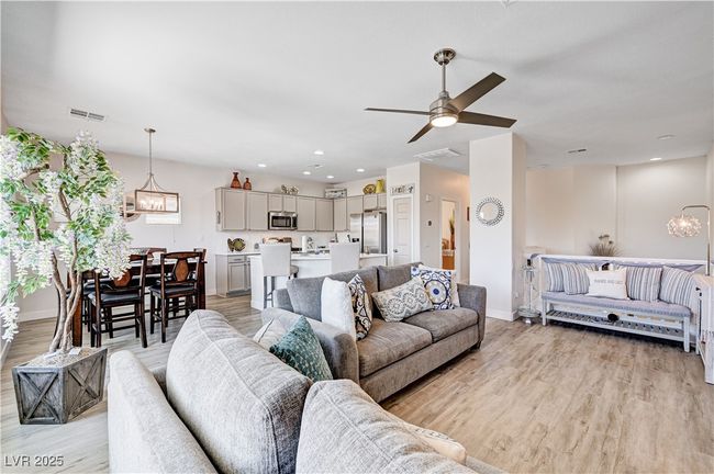 Living room with light wood-style floors, ceiling fan, a chandelier, and recessed lighting | Image 12