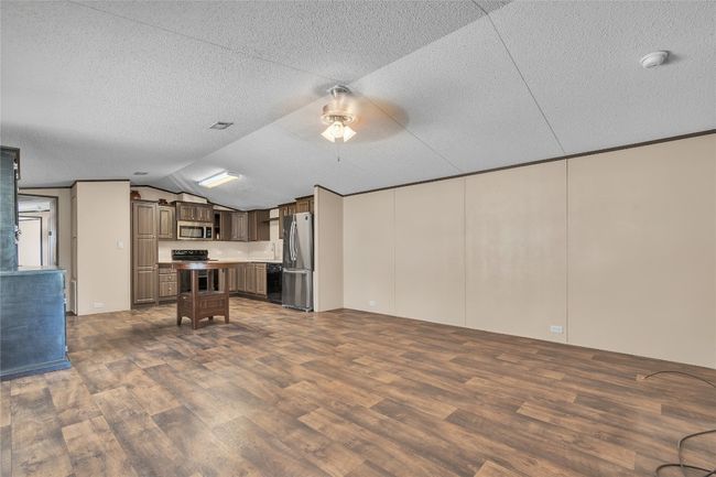 Kitchen featuring black appliances, dark wood-style floors, a textured ceiling, lofted ceiling, and light countertops | Image 5