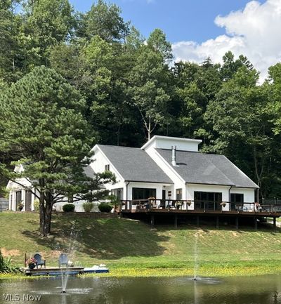 View of front of home with a deck with water view and a front yard | Image 1