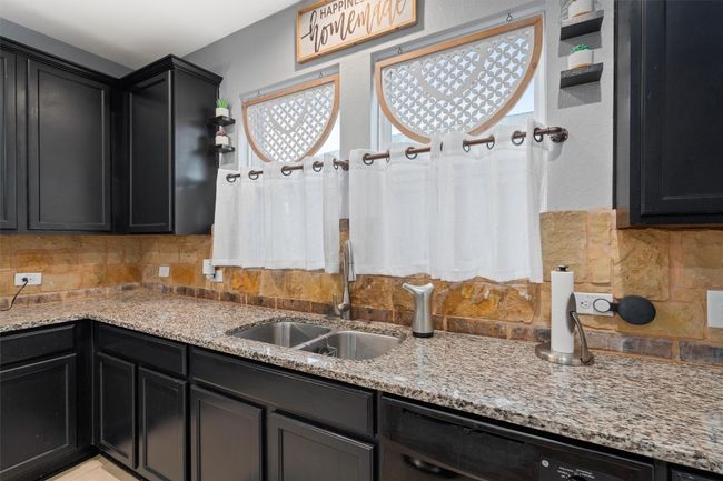 Kitchen featuring tasteful backsplash, dark cabinetry, and light stone counters | Image 6