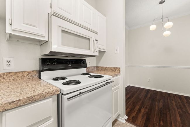 Kitchen featuring white cabinetry, white appliances, crown molding, and light countertops | Image 12