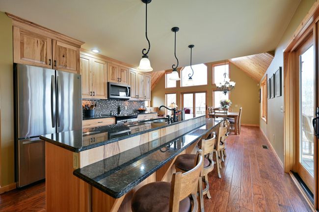 A view from the kitchen looking out to the open dining and living spaces with the deck to the right. The kitchen has a matching suite of stainless steel appliances. | Image 25