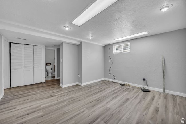 Below grade area featuring baseboards, light wood finished floors, and a textured ceiling | Image 18