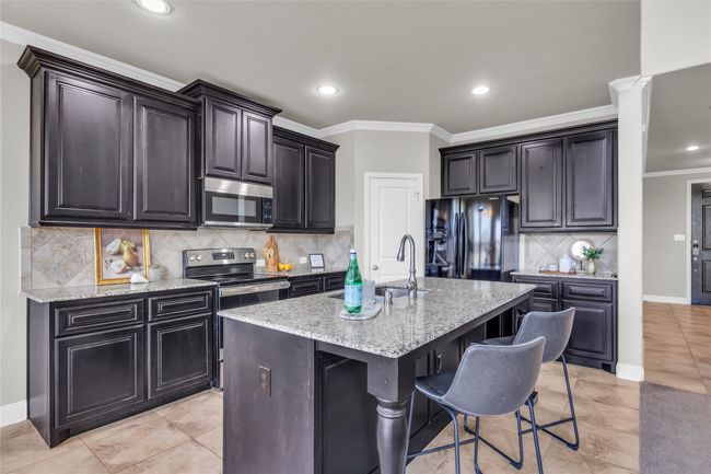 Kitchen with appliances with stainless steel finishes, a sink, light stone counters, an island with sink, and recessed lighting | Image 4