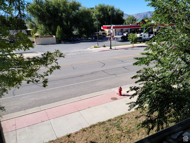 View of asphalt road featuring sidewalks, curbs, street lighting, and a mountain view | Image 30
