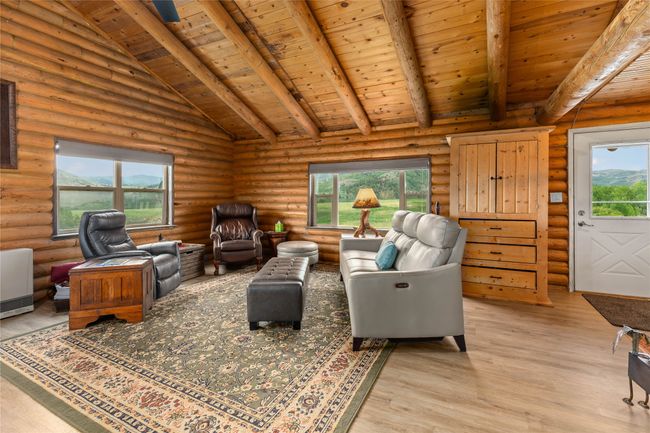 Living area featuring wooden ceiling, log walls, healthy amount of natural light, and light wood-style flooring | Image 12