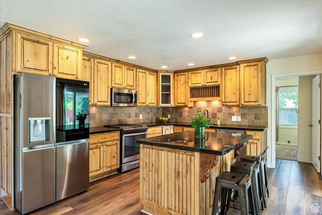 Kitchen with stainless steel appliances, dark wood-style floors, tasteful backsplash, a kitchen island, and recessed lighting | Image 18