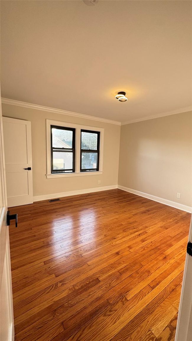Spare room with ornamental molding and wood finished floors | Image 17