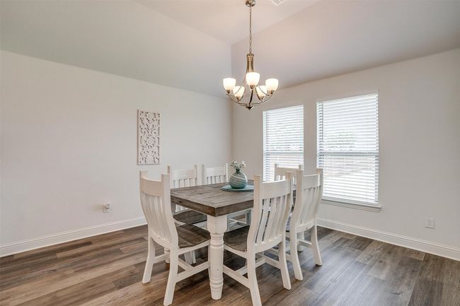 Dining room with a chandelier, wood finished floors, vaulted ceiling, and baseboards | Image 16