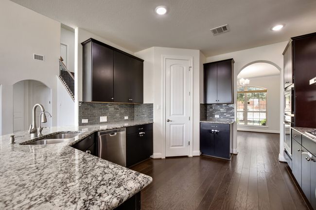 Kitchen featuring appliances with stainless steel finishes, arched walkways, light stone countertops, dark wood-style floors, and tasteful backsplash | Image 12