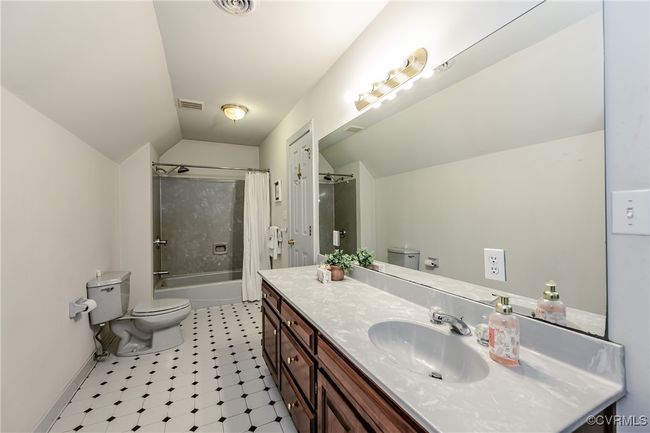 Full bathroom featuring toilet, vaulted ceiling, vanity, and shower / bath combo with shower curtain | Image 32