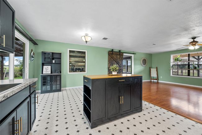 Kitchen featuring a barn door, light flooring, dark cabinetry, and a ceiling fan | Image 12