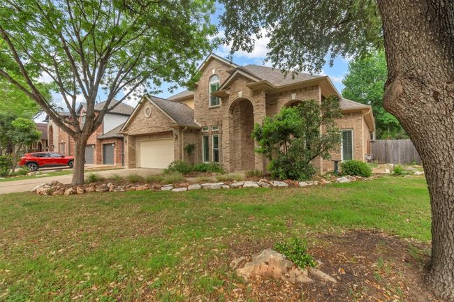 Traditional home featuring concrete driveway, brick siding, a front yard, and a garage | Image 13