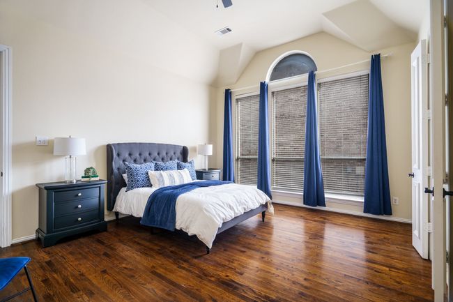 Bedroom with a ceiling fan, lofted ceiling, baseboards, visible vents, and wood flooring | Image 11