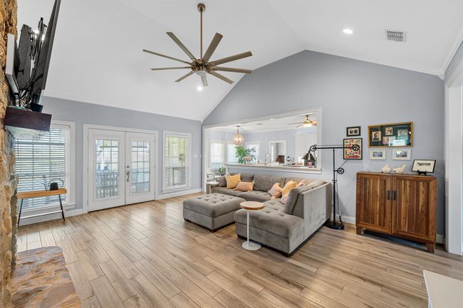 Living area featuring baseboards, light wood-style flooring, visible vents, ceiling fan, and high vaulted ceiling | Image 11