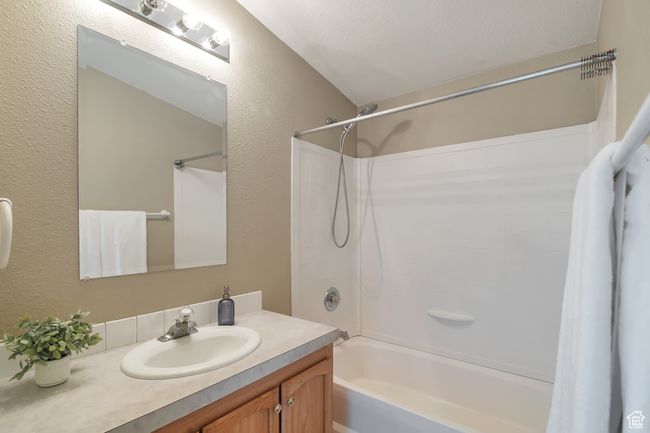 Bathroom with a textured wall, shower / tub combo with curtain, and vanity | Image 18