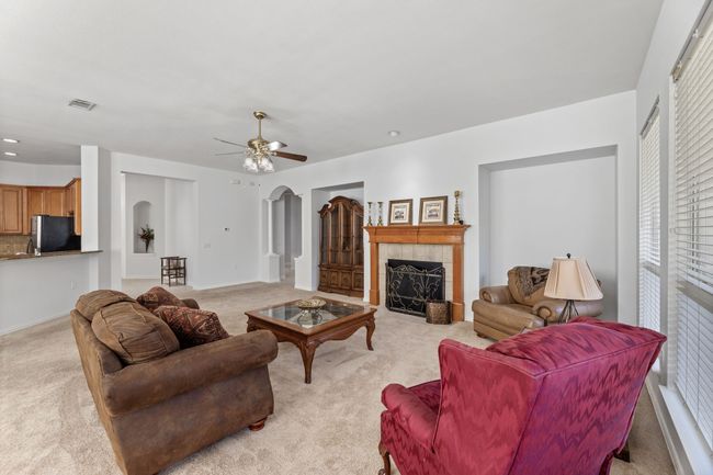 Living room featuring light colored carpet, a tiled fireplace, and ceiling fan | Image 12