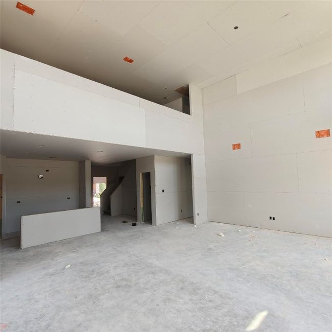Unfurnished living room with a towering ceiling and unfinished concrete floors | Image 4