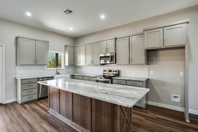 Kitchen with gray cabinets, dark wood-style flooring, stainless steel appliances, and visible vents | Image 7