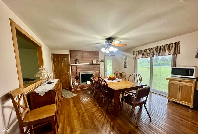 dining room featuring dark wood-style flooring, a fireplace, and a ceiling fan | Image 15