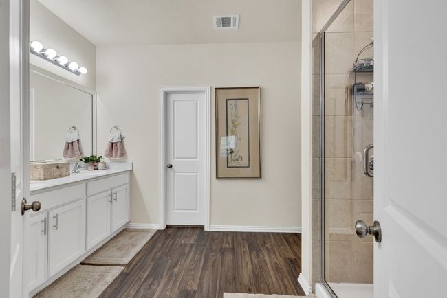 Bathroom with visible vents, baseboards, vanity, wood finished floors, and tiled shower | Image 20