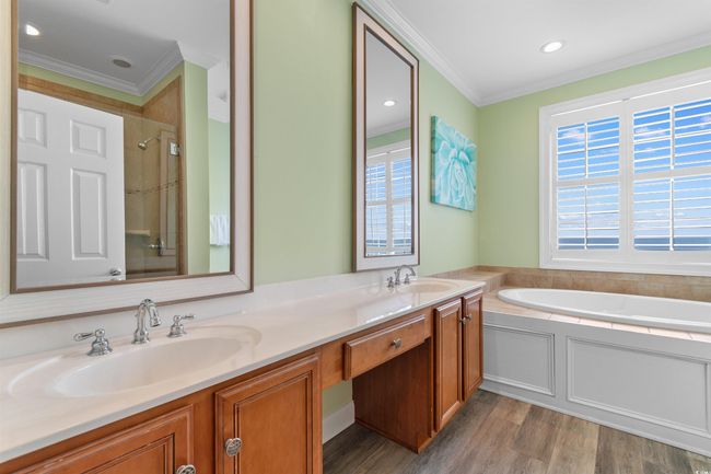 Oceanfront En Suite Bathroom with crown molding, double vanity, wood finished floors, a jetted garden tub, and a tile hower | Image 34